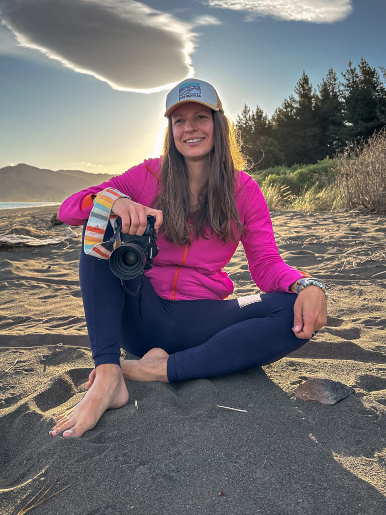at sitting on a black sand beach with her camera